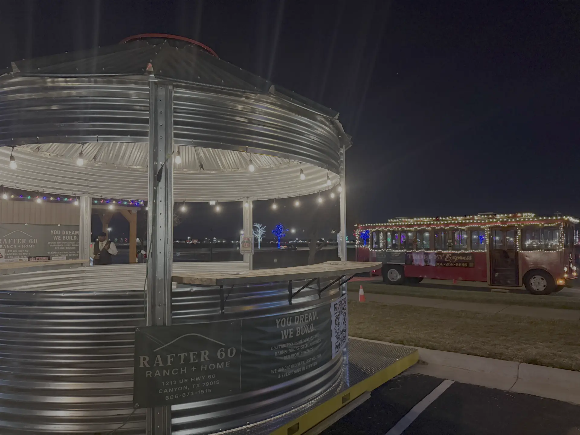 Binzebo bar build lit with string lights at night beside a holiday trolley at Rafter 60 Ranch + Home